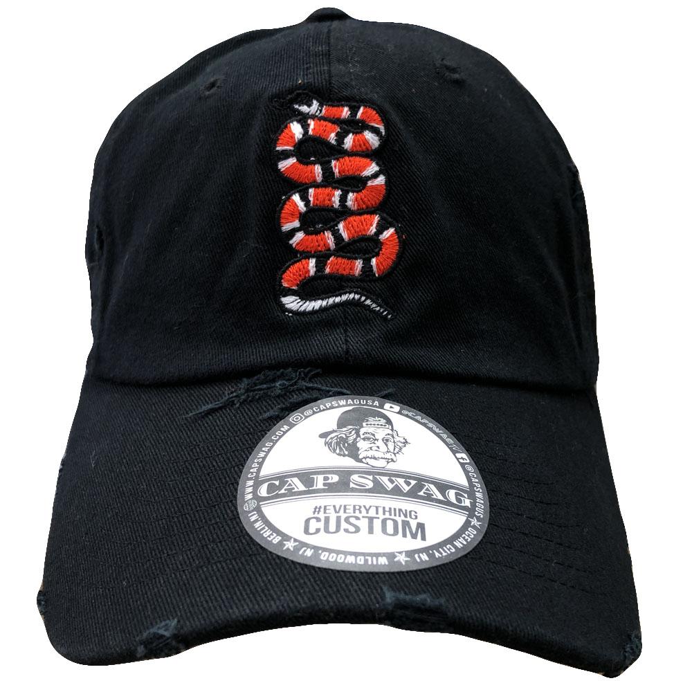 Embroidered on the front of this black distressed rattlesnake dad hat is a rattlesnake in red, black, and white