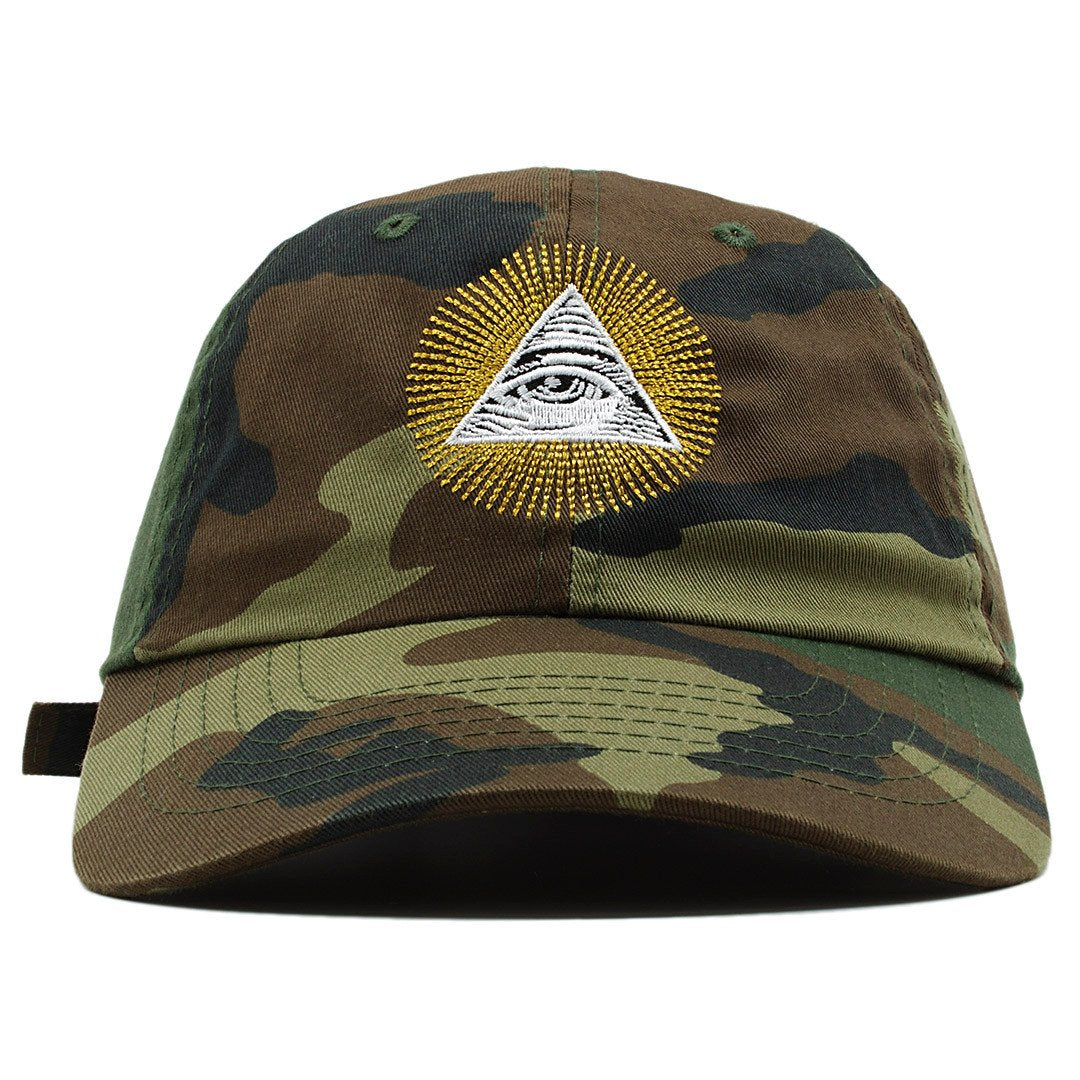 The All Seeing Eye Illuminati dad hat features the Illuminati pyramid embroidered on the front in white and black with rays surrounding it, embroidered in metallic gold thread.
